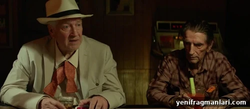 10 Iconic Harry Dean Stanton Performances 10 A smart suited man and a rough and ready man sit at a bar in the dark, seemingly contemplating something.