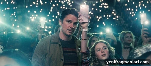 Josh Hartnett and Ariel Donoghue at a music concert, the lights on their phone lighting up the dark.