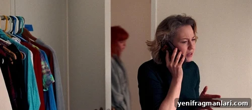 Carrie Coon speaks on the phone as Natasha Lyonne walks by in the background of 2024 Netflix film 'His Three Daughters'.