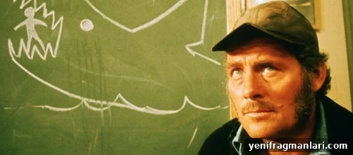 10 Unforgettable Jaws Moments 10 Quint sits in front of a chalk drawing of a shark eating a person in 'Jaws' (1975).