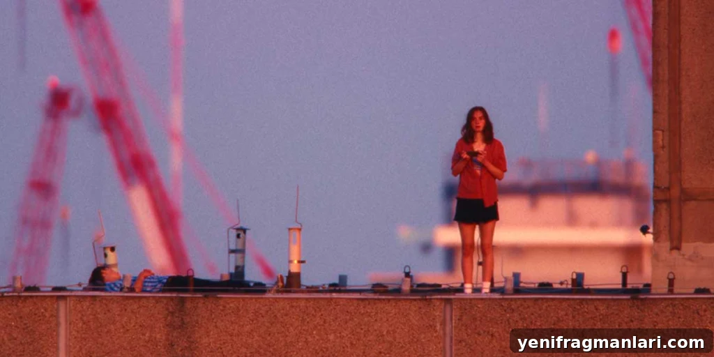 Everytime Review: Grief, Memory, and a Hidden Glimmer 3 A young woman stands on a rooftop at dusk while another person lies nearby, framed against a pink and blue sky in Everytime.